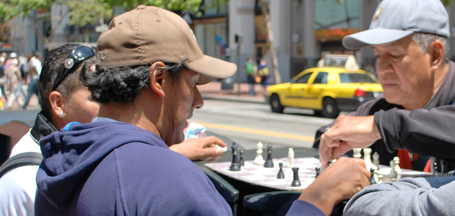 two men playing chess on sidewalk