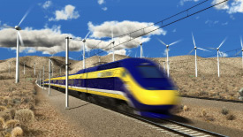 High speed train travelling past large wind turbines